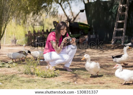 Beautiful young woman taking a few pictures of ducks at a farm
