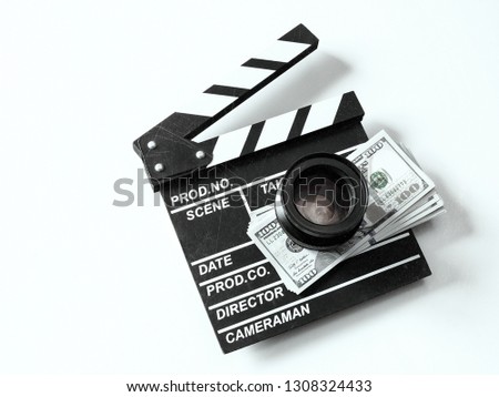 Clapperboard, camera lens and dollar bills shot from above on a white background