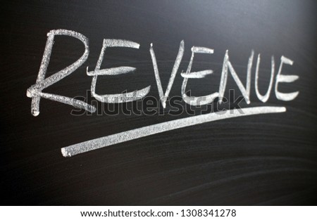 The word Revenue written by hand in white chalk on a blackboard and photographed at an angle
