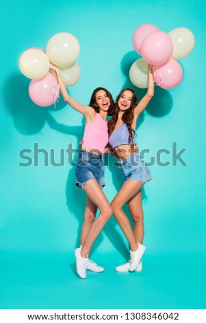 Full length body size photo beautiful cheerful two wavy she her ladies cheerleaders colorful balloons hands arms  wearing shiny jeans denim shorts tank tops isolated teal bright vivid background