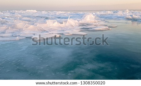 Snow, ice and waves at sunset. Winter day