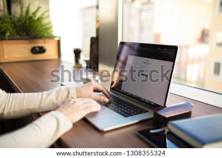 Closely woman professional web content editor keyboarding on laptop computer with blurred applications on screen, sitting at workplace in co-working space. Blogger typing article on notebook device