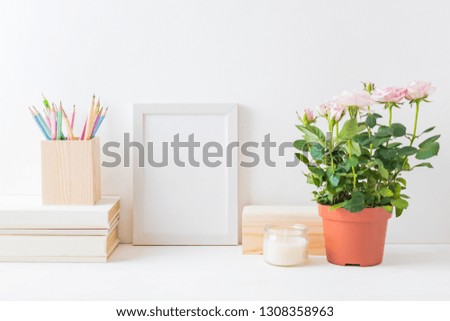 Home interior with decor elements. White frame, pink roses in a pot, interior decoration