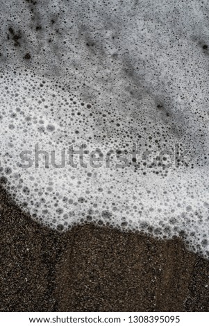 Abstract water bubbles on a black and brown sand beach