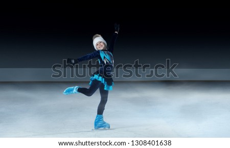 view of child  figure skater on dark ice arena background