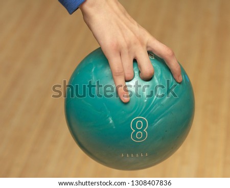 Green ball number eight in the hand of a bowling player