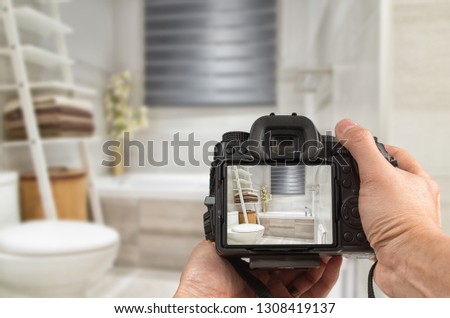 Hands holding DSLR capturing interior of a modern bathroom