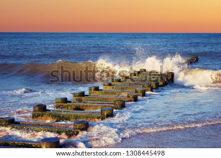 Wood pier post in Maryland Beach with rolling waves.  with Orange sky