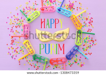 Purim celebration concept (jewish carnival holiday) with mask mask over wooden purple background.