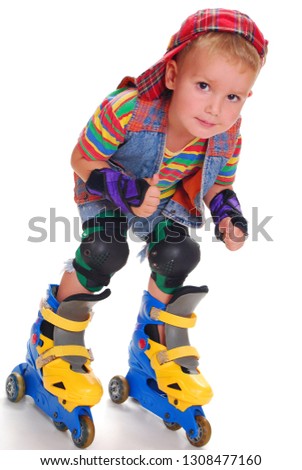 A little boy in bright clothes riding roller skates.