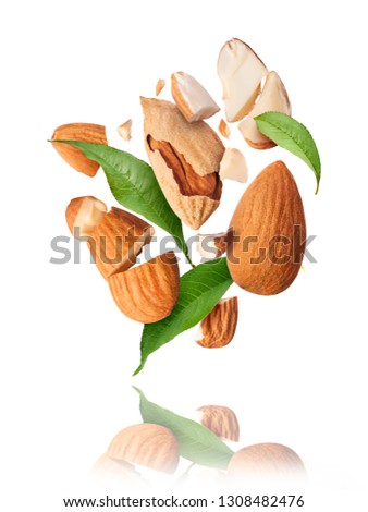 Flying in air fresh raw whole and cut almonds  isolated on white background. Concept of Almonds is torn to pieces close-up. High resolution image