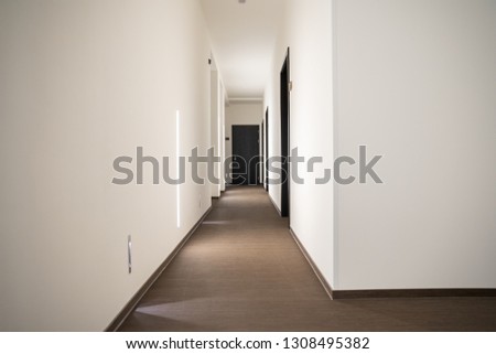 white hotel hallway with many doors and lights Royalty-Free Stock Photo #1308495382