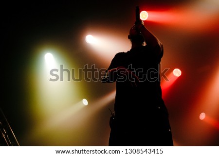 A silhouette of a rap artist is on the stage. Green and red light background. A music show
