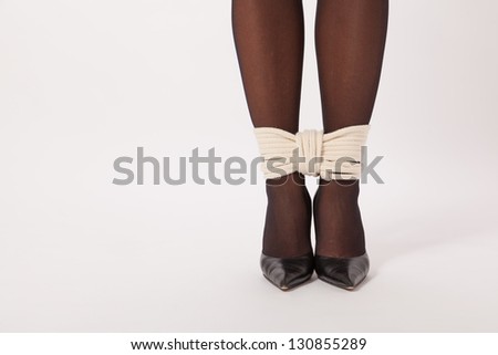The feet of a young woman are tied with a rope