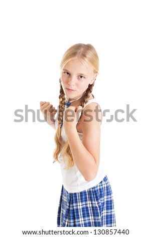 Schoolgirl blonde with two braids in school uniform. Girl in a fighting stance with clenched fists. Studio shot, isolated on white background.