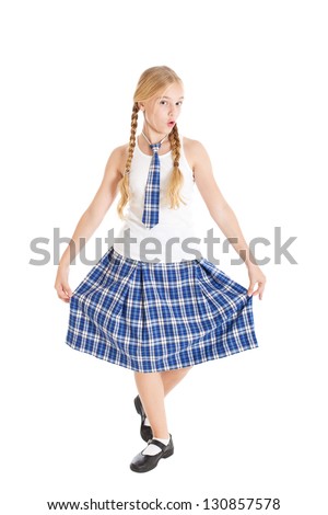 Schoolgirl blonde with two braids in school uniform. Girl dancing and doing a curtsy. Kissing lips. Studio shot, isolated on white background.