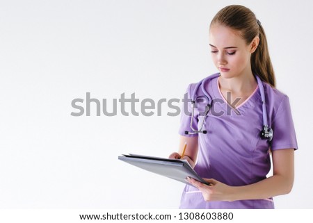 Nurse girl doctor on gray background holding a folder in her hands smiling writes a blonde beautiful. Concept student trainee report task attentiveness.