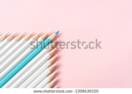 Business and design concept - lot of white pencils and one color pencil on pink paper background. It's symbol of leadership, teamwork, success and unique.