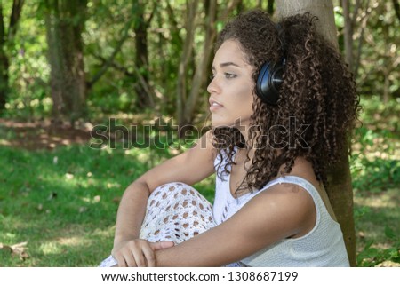 Beautiful afro american girl listening music in a park