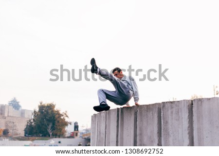 Caucasian man trains parkour while jumping over a high top.