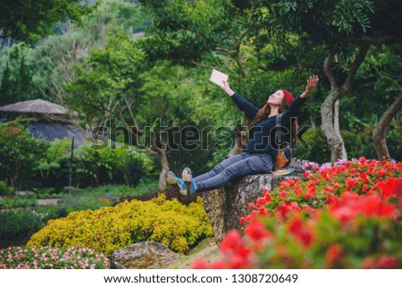 woman travel nature in the flower garden. relax sitting on rocks and reading books In the midst of nature at national park doi Inthanon.