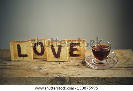 Toast Bread with the Word LOVE painted with hazelnut chocolate spread and a cup of tea