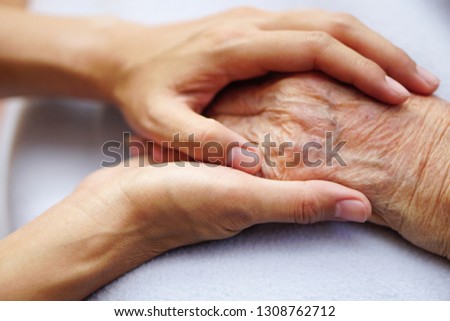 Touching or holding hands, asian senior or elderly old woman placed on a blue cloth with love, care, encourage and empathy.