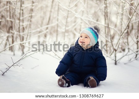 happy smiling baby boy sitting on snow Royalty-Free Stock Photo #1308769627