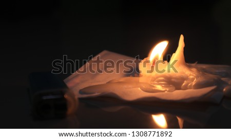 One light candle burning brightly on the tissue in the black background