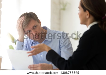 Confused hr manager and job candidature sitting at negotiation room, company representative hold head with hand looking at deceitful female feels perplexed. Unsuccessful passing of interview concept Royalty-Free Stock Photo #1308783595