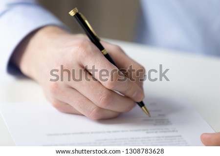 Customer sitting at table holds pen filling contract official document buy or sell property getting insurance or affirms employment agreement, close up paper and hand. Making successful deal concept