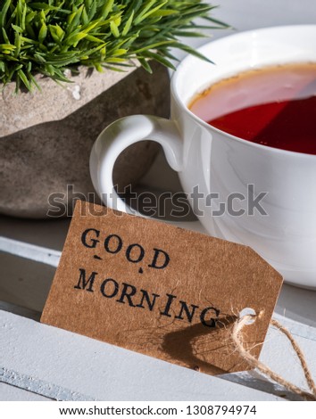 Close up image of GOOD MORNING label tag with a cup of tea on wooden table. Selective focus.
