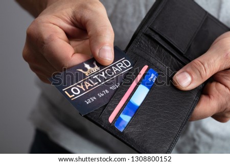 Close-up Of A Person's Hand Removing Black Loyalty Card From Wallet Royalty-Free Stock Photo #1308800152