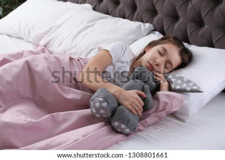 Beautiful little girl with toy rabbit sleeping in bed