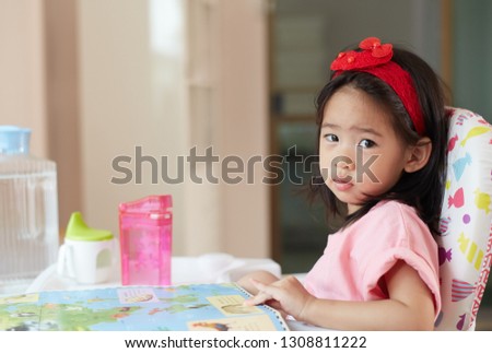 asian Little girl with book on high chair, she funny and happy