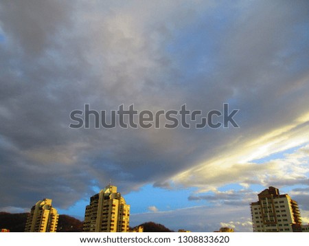 The sun shifts behind the clouds above the tops of the residential buildings
