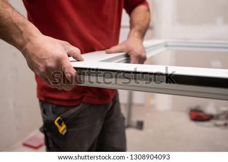 close up of worker assembling an aluminium door in workshop Royalty-Free Stock Photo #1308904093