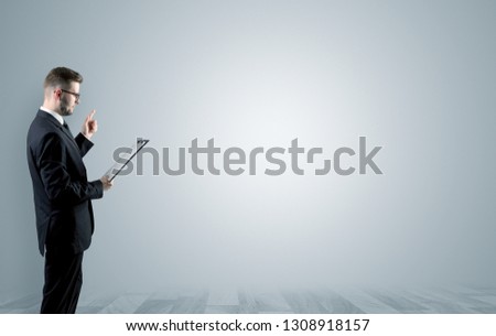 Elegant businessman standing and presenting something in an empty space with floor