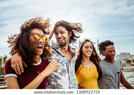 Group of men and women walking down the street talking and having fun. Multi-ethnic friends walking outdoors together. Royalty-Free Stock Photo #1308922759