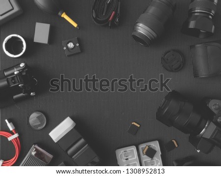 top view of work space photographer with digital camera, flash, cleaning kit, memory card and camera accessory on black table background with copy space.
