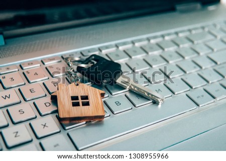Metallic key on key ring with house symbol lying on laptop keyboard. Real estate and internet concept. Buing property via internet. Online search for dwelling in web. Purchasing house. Website