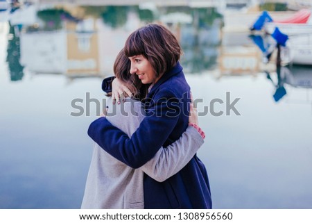 Two happy friends or sisters hugging on the street. Lifestyle outdoors. Port background