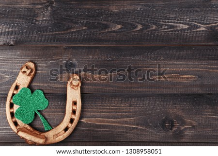 St.Patrick's Day. Golden horseshoe with clover leaf on wooden table