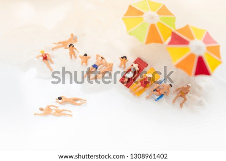 Miniature people: Tourists sunbathe on beach with copy space for text using as background summer traveling, exploring the world, business trip concept.