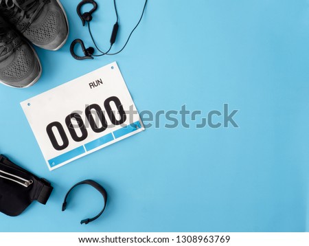 top view of Running Event concept with running shoes, bib number and running accessories on blue background. Royalty-Free Stock Photo #1308963769