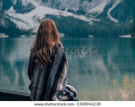 a tourist standing in front of the lago di braies in the italian alps and dolomites
