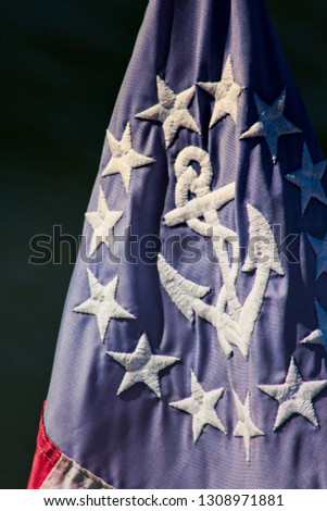 Bright red white and blue vintage nautical American sailing flag flying off a boat in the summer.  Royalty-Free Stock Photo #1308971881