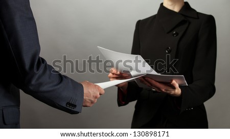 Businessman and businesswoman interchange of documents, grey background
