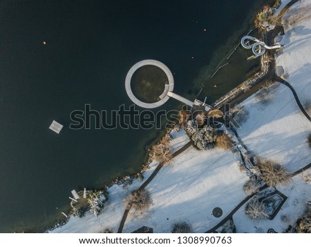 Aerial view of water slide on lake shore in winter time. Snow covered surface of leisure park in Switzerland.