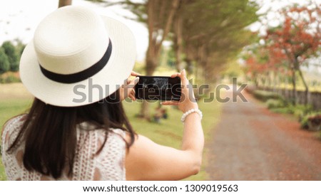 Asian traveler woman with hat using smartphone taking pictures road upcountry and natural on summer day. Traveler, holiday, vacation and natural concept